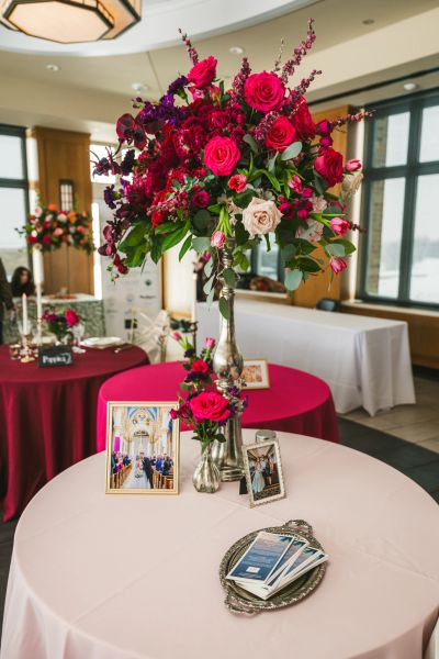 Elegant floral centerpiece with red and pink roses on a decorated table at an event venue.