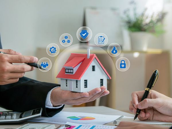 A person holding a model of a house with digital icons floating above it.