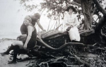 Three people sitting on a tree trunk.