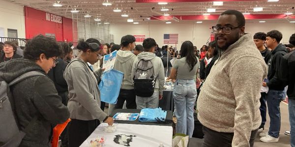 People gathered at indoor event with tables and displays.