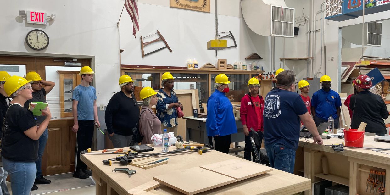 Group of people in hard hats inside a workshop.
