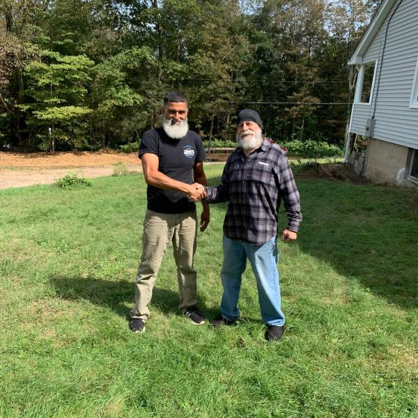 Two men shaking hands outdoors on a sunny day.