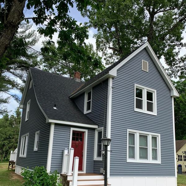 Blue two-story house with white trim and a red door.