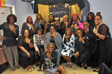 Group of women celebrating with a 'Happy' banner in the background.