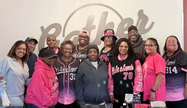 A group of people smiling in pink and black sports jerseys.