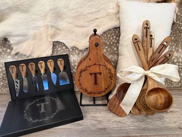 Wooden kitchen utensils and cheese knives with engraved 'T' initials.