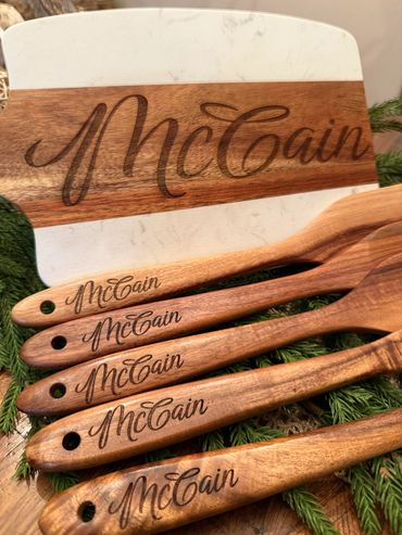 Wooden kitchen utensils and cutting board engraved with the name McCain.