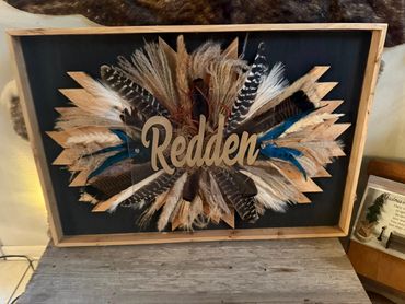 Decorative wooden frame with feathers and the name 'Redden' in the center.
