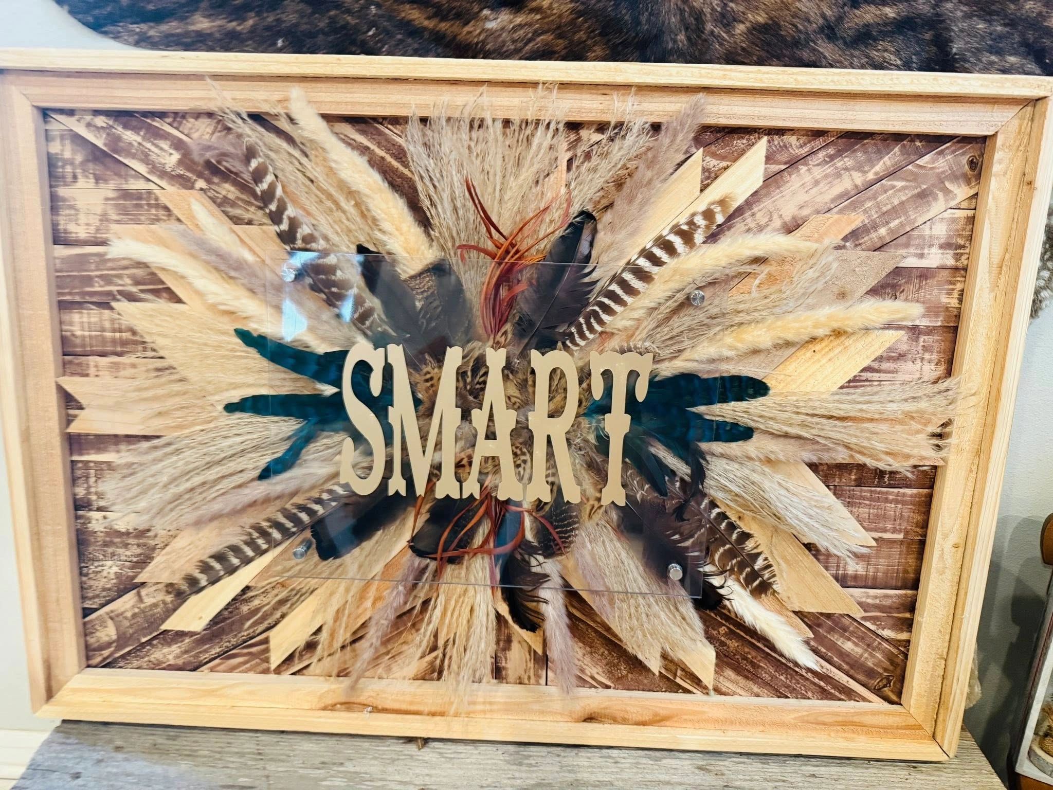 Decorative wooden frame with feathers and the word 'SMART' in the center.