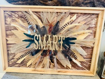 Decorative wooden frame with feathers and the word 'SMART' in the center.