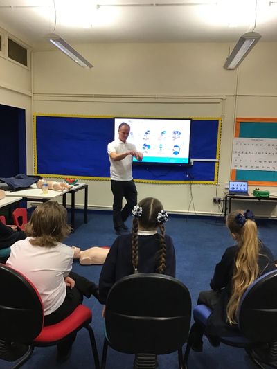 Trainer teaching children in nursery school how to give first aid
