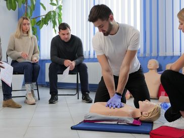 Instructor demonstrating CPR on mannequin at first aid training course.
