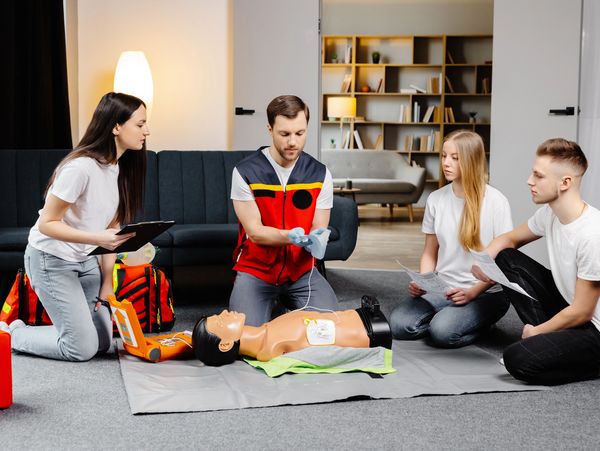 Young man instructor helping to make first aid heart compressions