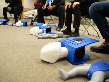 A classroom of students learning the basics of first aid with a doll