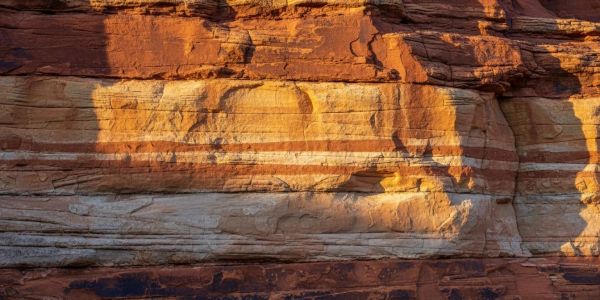 Layered sandstone rock formations with orange and white bands.