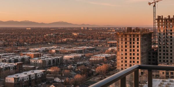 Urban landscape with construction and mountains at sunset.