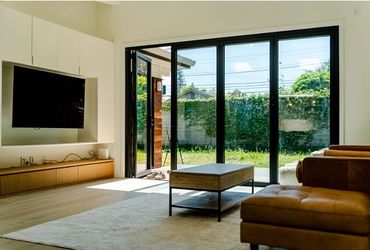 Bright living room with large glass doors opening to a garden.