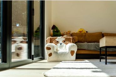 Cozy dog-shaped plush chair in a sunlit living room corner.