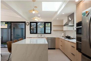 Modern kitchen with marble island and wooden cabinets.