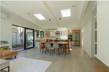 Modern open-concept kitchen and dining area with skylights and large sliding doors.