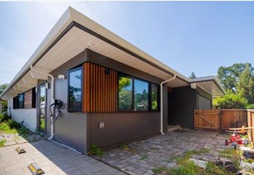 Modern single-story house with dark exterior and wooden accents.