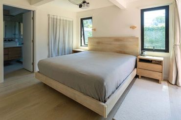 Minimalist bedroom with wooden bed frame and natural light.