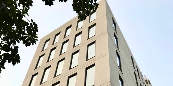 8 floor high-end commercial property facade. Sleek rectangle windows and light warm grey color.