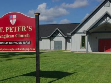 Sign for St. Peter's Anglican Church with the building in the background.