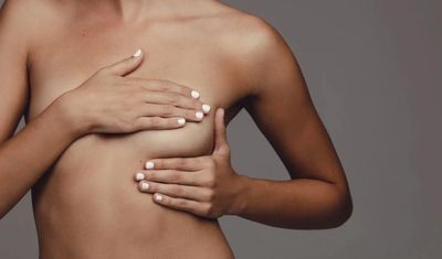 Woman performing a breast self-exam with hands covering her chest.