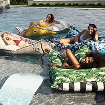 Family and friends relaxing in a pool on loungers