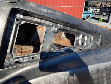 Close-up of a car's dashboard frame under restoration outdoors.