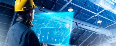 Engineer wearing a yellow helmet using futuristic holographic interface.