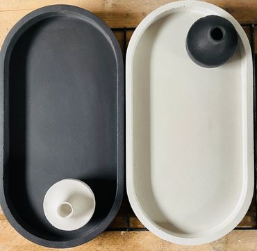 two concrete trays side by side, black and white like ying and yang with two candlestick holders.