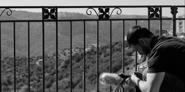 Music production artist in residence recording on balcony overlooking mountains in sicily