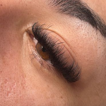 Close up image of a clients lashes with a 5D C curl wispy set.