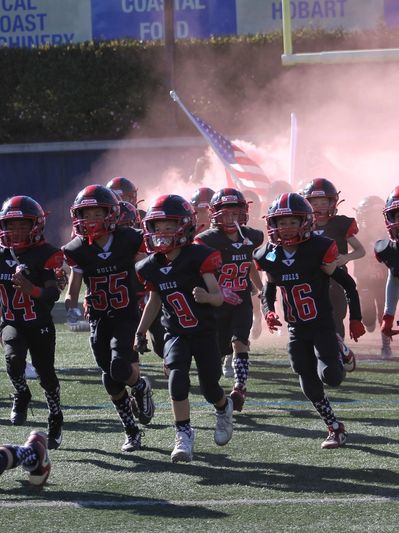 Toro Bulls Football & Cheer running onto the field.