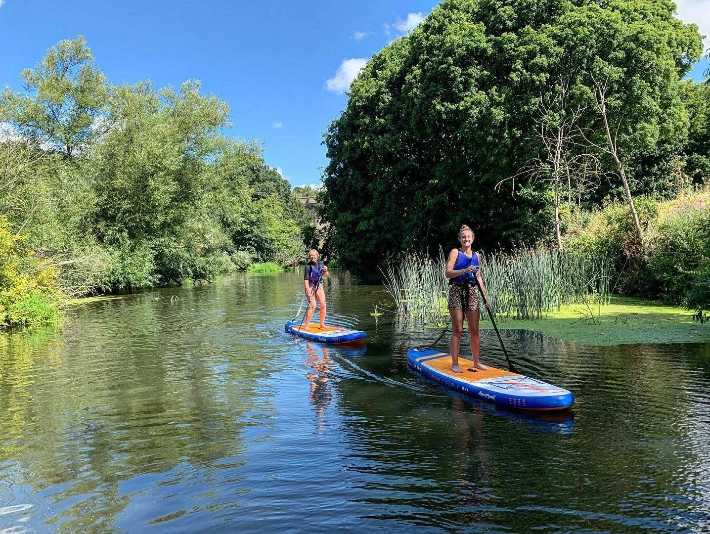 Two friends paddleboarding down the River Avon