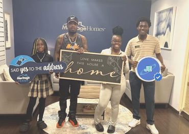 Family celebrating their new home with signs at Meritage Homes.