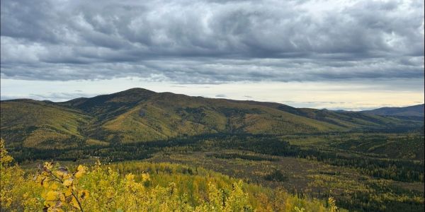 Cloudy sky over expansive autumn mountains and forests.