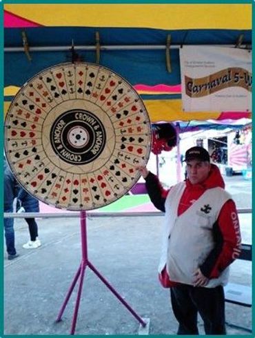 Le bénévole Marc fait tourner la roue au 5-Way Carnival.