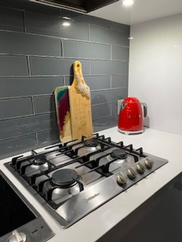 Modern kitchen with gas stove, colorful cutting boards, and a red kettle.