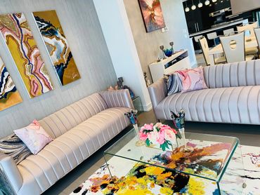 Modern living room with beige sofas and colorful abstract art.