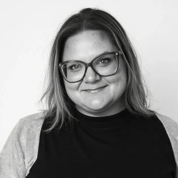 Smiling woman with glasses in a black and gray outfit.
