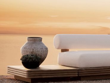 Modern outdoor seating with pottery during sunset by the sea.