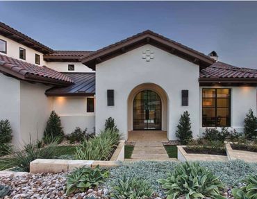 Modern Mediterranean-style house with arched entrance and landscaped garden.