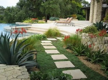 A serene garden path leads to a poolside terrace with lounge chairs.
