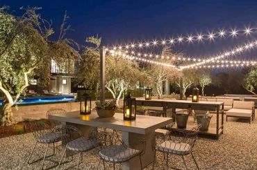 Outdoor dining area with string lights and lanterns at night.