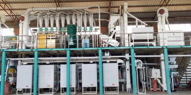 Large industrial machinery setup inside a factory with pipes and control panels.
