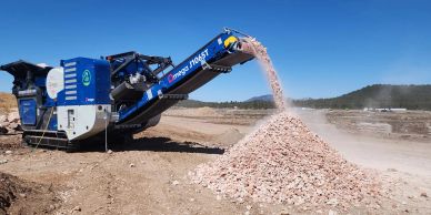 A machine sorting and piling crushed stones outdoors.