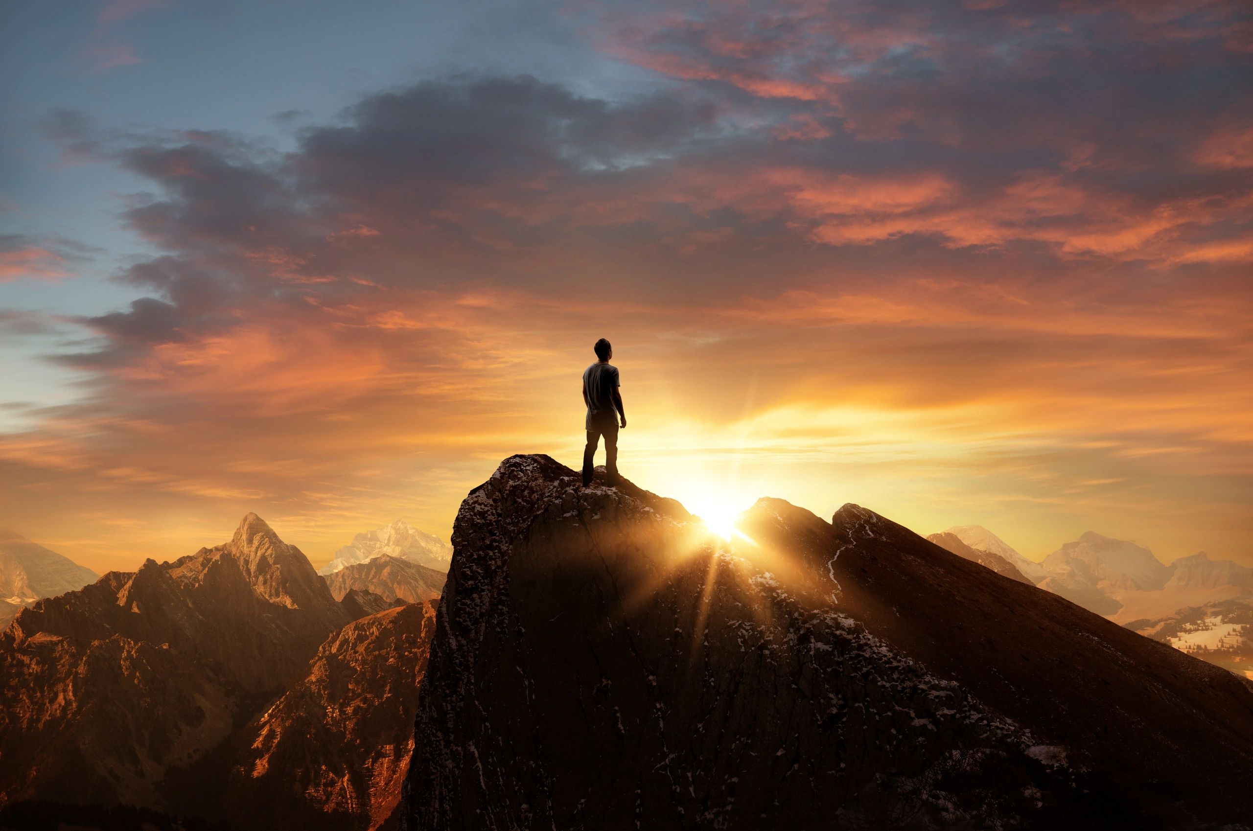 A man standing on top of a mountain as the sun sets